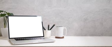 Dizüstü bilgisayar, kalem tutacağı, kahve fincanı ve defterleri beyaz masaya koyun. Alan kopyala, reklam tasarımın için boş ekran.