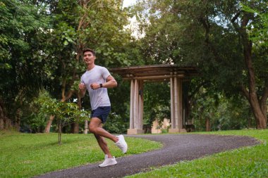 Sabahları halka açık parkta koşan genç bir sporcu. Fitness, egzersiz ve sağlıklı yaşam tarzı konsepti.