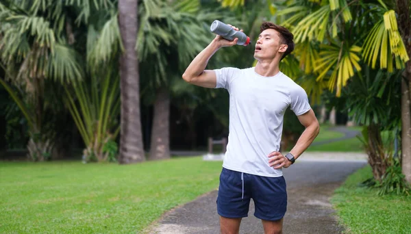 Sportowiec Pije Wodę Butelki Porannym Joggingu Tropikalnym Parku Koncepcja Zdrowego — Zdjęcie stockowe