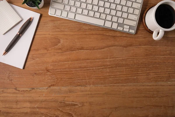 在木制桌子上安装无线键盘 笔记本和咖啡杯的简易工作场所的顶部视图 — 图库照片
