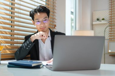 Focused handsome businessman working with computer at bright office.	