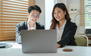 Smiling young businessman explaining online information to his colleagues.	