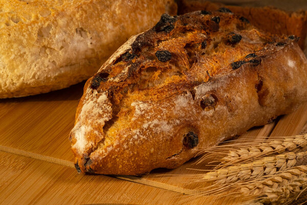 Close up view of fresh bread and wheat on the wooden table.