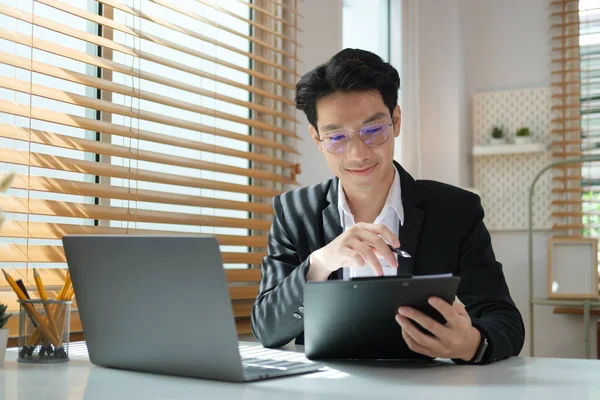 Focused Asian Businessman Writing Important Information Notepad Using Laptop Working — 图库照片