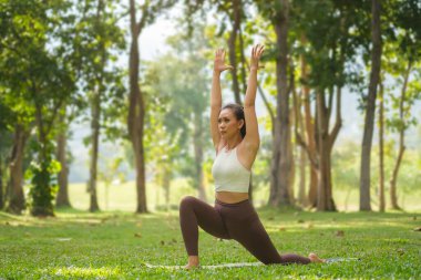Sportif genç kadın yoga yapıyor, Virabhadrasana egzersizinde duruyor ya da Savaşçı 1 poz veriyor..