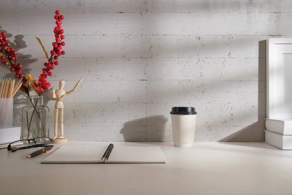 stock image Home office desk with notepad, picture frame, books and paper cup of coffee.