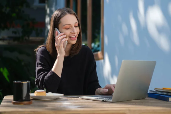 Приємна Молода Жінка Використовує Ноутбук Розмовляє Мобільному Телефоні Відкритому Повітрі — стокове фото