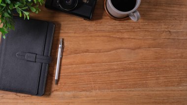 From above view of retro camera, coffee and notebook on wooden table. Top view with copy space.	