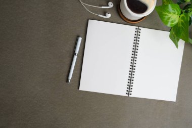 Boş not defteri, kulaklıklar, kahve fincanı ve gri arka planda saksılar.. 