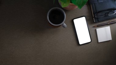 Düz telefon, boş ekran, yapışkan not, kahve fincanı ve gri masada kitaplar. Metnin için boşluk kopyala.