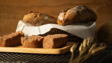 Rustic crusty loaves of bread with grain in wicker basket on rustic wooden table.	