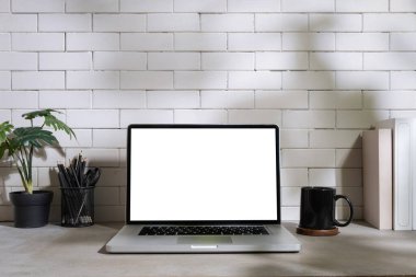 Stylish workplace with laptop, coffee cup, houseplants and stationery on table.	