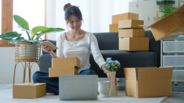 Genç bir kadın, küçük bir işletme sahibi olarak müşteriye teslimat için bir paket ürün hazırlamaya başlıyor..