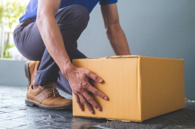 Teslimatçının karton kutuyu girişe koyarken görüntüsü kesilmiş. Kurye ve nakliye hizmeti kavramı.
