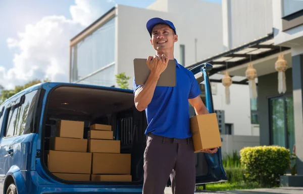 Image of delivery service worker holding cardboard boxes standing at suburban street. Post package delivering and transportation concept.
