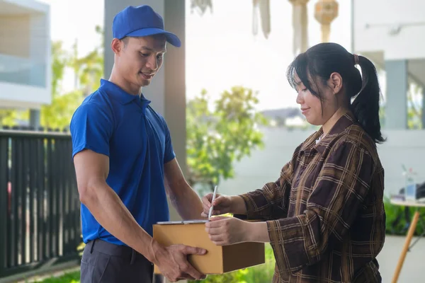 Tatmin olmuş genç bir kadın dijital tablete imza atıyor, erkek kuryeden paket alıyor..