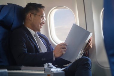 İş adamı uçuş sırasında Window 'un yanında rahat koltukta oturuyor..