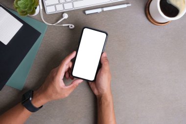 Reklam tasarımınız veya bilgi içeriğiniz için boş ekranlı cep telefonu tutan ellerin üst görünümü.