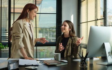 Modern ofiste proje ve planlama konularını tartışan iki kadın yönetici..