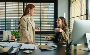 Genç başarılı bayan çalışanlar proje sonuçlarını tartışıyor ve ofiste iş planlıyorlar..