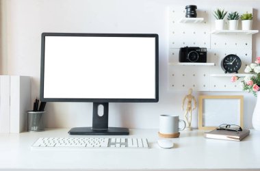 Front view view of blank desktop computer scree,n books, coffee cup and coffee cup on white desk.