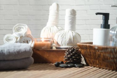 Burning candles for relax spa massage, towels, herbal compress balls and body treatment on wooden table.
