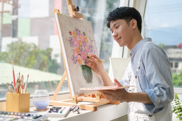 Creative man painting on canvas  in with oil paint in bright modern art studio. 