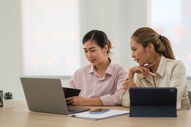Shot of two young workers looking at laptop screen working on a project of company.