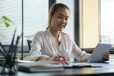 Stylus kalem kullanan mutlu iş kadını dijital tablet hakkında bilgi yazıyor..