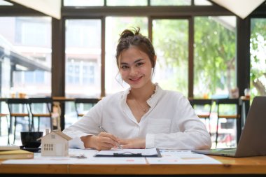 Dizüstü bilgisayar kullanan başarılı girişimci ve parlak modern ofiste muhasebe belgesi ile çalışıyor.