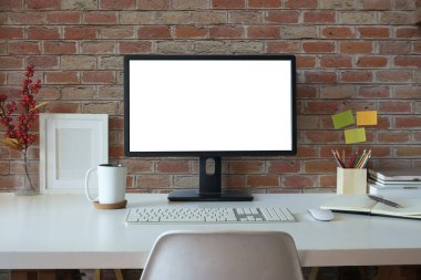 Front view blank desktop computer screen, picture frame and pencil holder on white table.