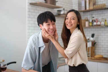 Romantic young couple enjoying spending time together while standing in modern kitchen at home.