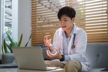 Smiling man doctor wearing white medical coat and stethoscope looking giving online consultation for domestic health treatment.