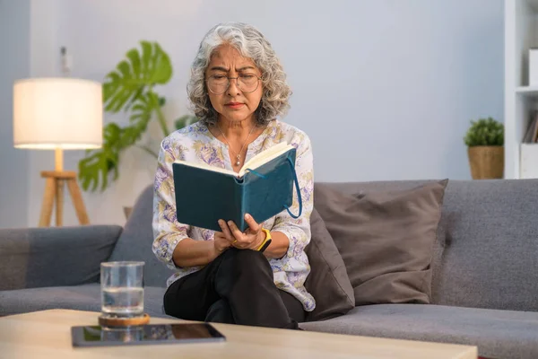 Happy Retired Woman Sitting Comfortable Sofa Reading Interesting Book Enjoying — Zdjęcie stockowe