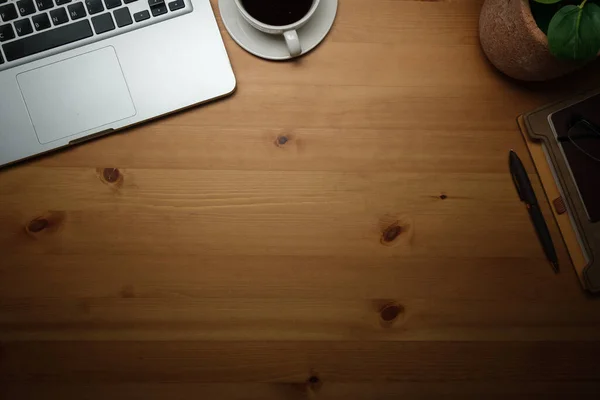 stock image Simple working desk with laptop computer, coffee cup, notebook and houseplant on wooden table. Top view with copy space.