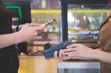 Female customer paying bill through smart phone.	