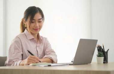 Thoughtful asian businesswoman checking financial reports at her office desk.	