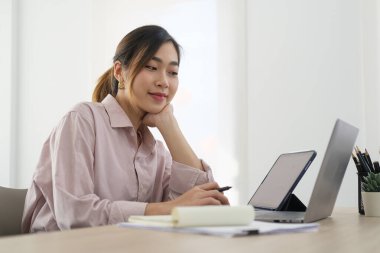 Konsantre kadın iş adamı parlak bir ofiste oturup bilgisayar ekranında finansal grafiği analiz ediyor..