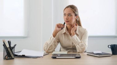 Thoughtful asian businesswoman sitting front of tablet at bright office and looking through window.	