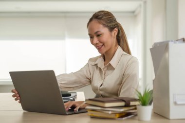 Asian female office worker using laptop computer at comfortable workplace.	