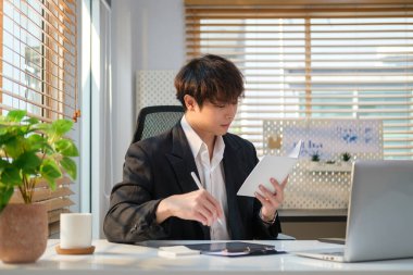 Handsome young businesspeople working with laptop computer and writing new idea on notebook.	