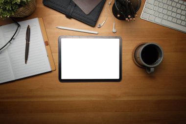 Dijital tabletli ahşap çalışma masası, kahve fincanı, gözlük ve defter. Kopyalama alanı olan üst görünüm.