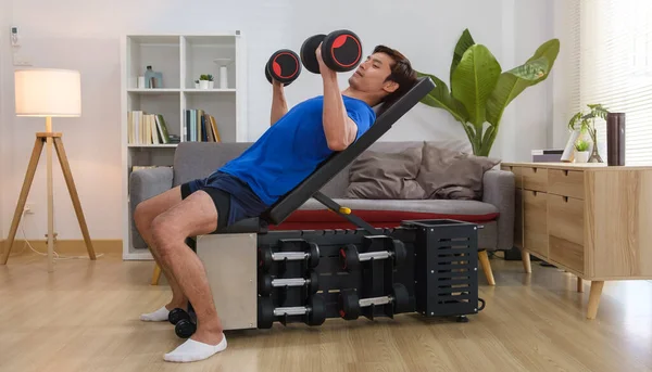 stock image Asian man in sportswear lying on a sports bench and lifts dumbbells. Bodybuilding and healthy lifestyle concept.