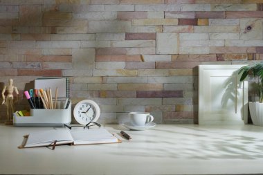 Resim çerçeveli yaratıcı tasarımcı çalışma alanı beyaz masa üzerinde kırtasiye ve saksı bitkisi oluşturur.