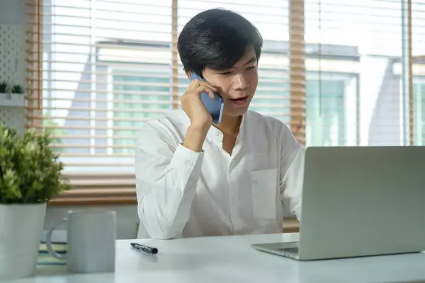 一位英俊的亚洲男人企业家 坐在现代写字楼里进行愉快的电话交谈 — 图库照片