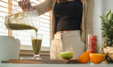 Sağlıklı genç bir kadın reen sebzeli smoothie 'yi bardağa dolduruyor. Sağlıklı beslenme, sağlık, beslenme ve vejetaryen.