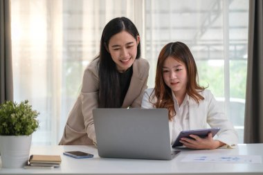 Dost canlısı bayan ofis çalışanı sonuçları tartışıyor ya da meslektaşıyla dizüstü bilgisayarında yeni bir proje sunuyor..