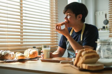 Hoş bir milenyum adamı mutfakta tost ve sütle kahvaltı yapıyor..