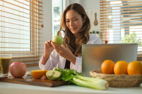 漂亮的女性营养师拿着一个绿色的苹果和放大镜 在办公室与节食计划一起工作 保健和饮食概念 — 图库照片