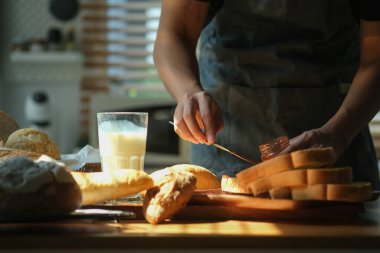 Adam kahvaltı hazırlıyor, ev yapımı çilek reçelini tost üzerine yayıyor..